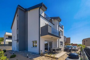A modern two-story house with a balcony, a patio with outdoor furniture, and a carport. - Holiday house AusCro Dreams (Punat)