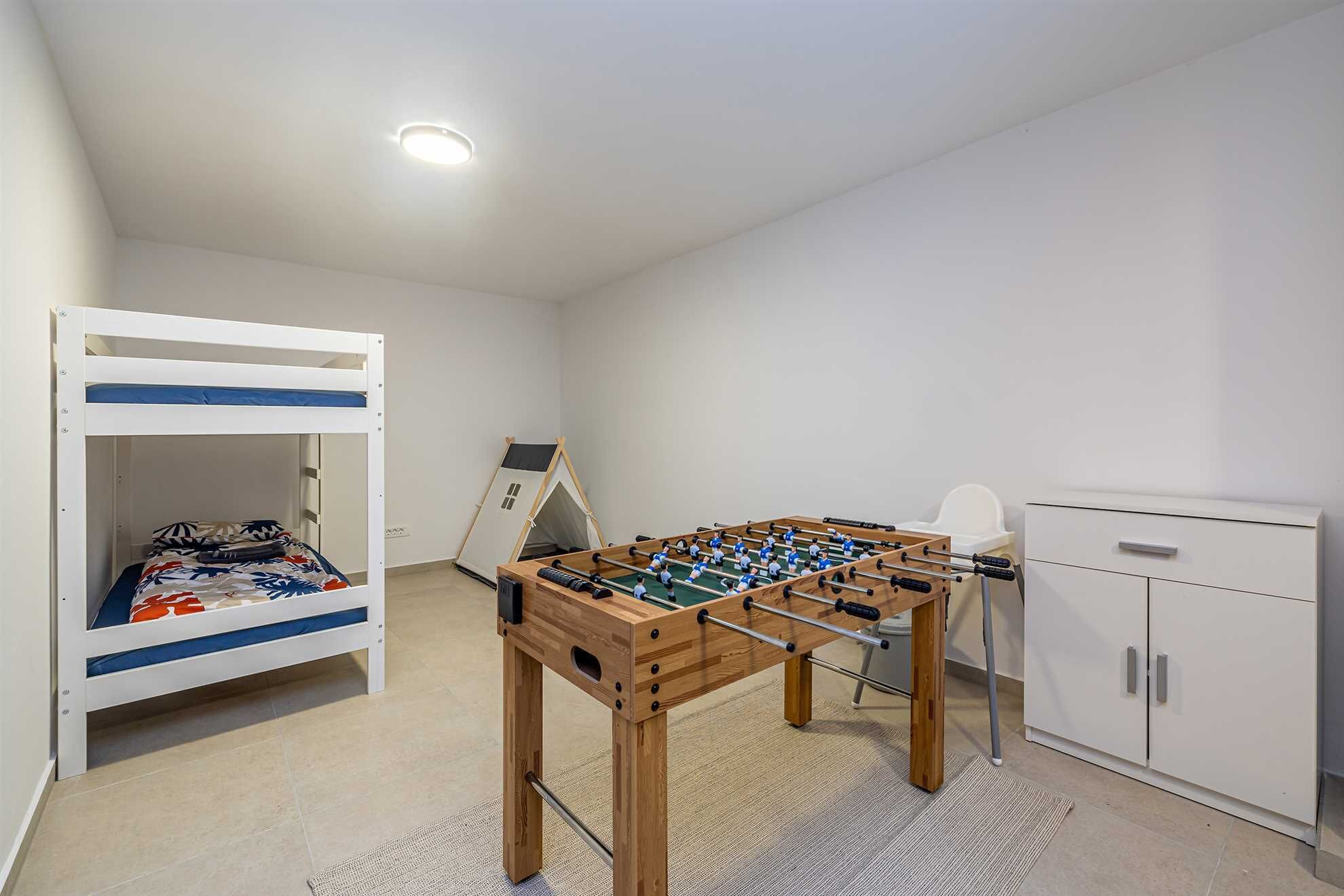 Ein Zimmer mit Etagenbett, Kicker, Zelt und Schrank.