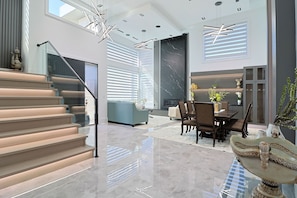 A modern interior with a staircase, a dining area, and a living space with a large window and decorative elements.