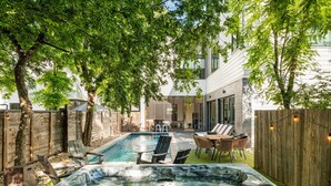 Een achtertuin met een hottub, lounge stoelen en een houten omheining.