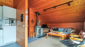 A wooden cabin interior with a kitchenette, a sofa, a coffee table, and a fireplace. - 2 bedroom nice home in Westende (Westende)