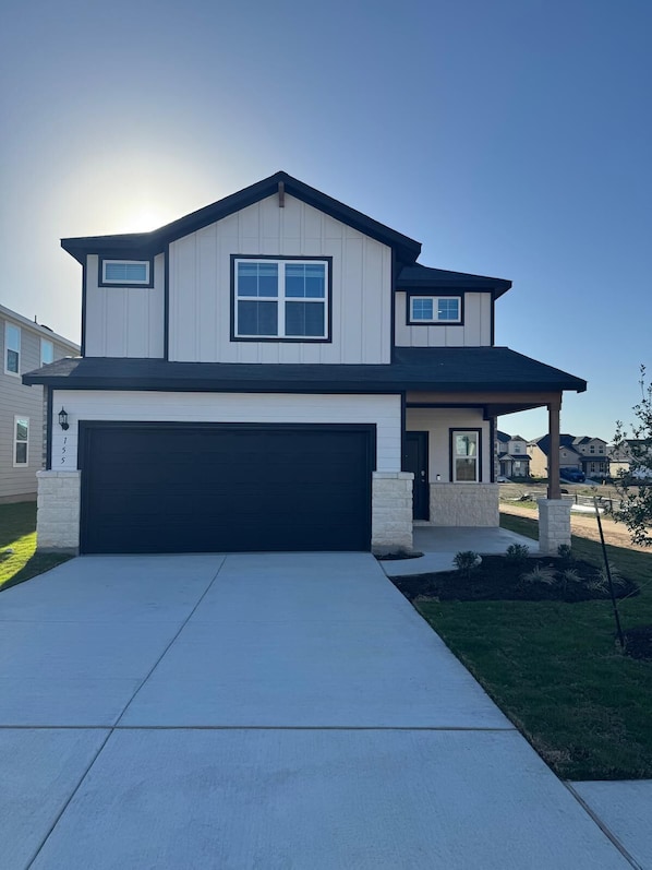 A two-story house with a garage, a covered porch, and a well-maintained lawn. - Charming 4-bedroom house in enjoyable Buda in sunfield community with Lazy River (Buda)