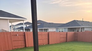 Ein Garten mit Holzzaun, Beton Terrasse und Metallpfahl.