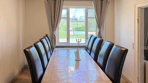 A dining table with six chairs, a candle, and a view through a window. - Stunning home in Lemvig with WiFi (Lemvig)