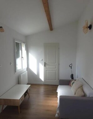 Ein Zimmer mit einem Bett, einer Sitzbank, einer Heizung, einer Tür und einem Fenster.