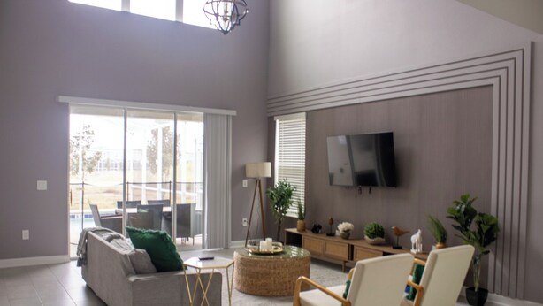 A modern living room with a sofa, chairs, a TV, and a dining area with a table and chairs.