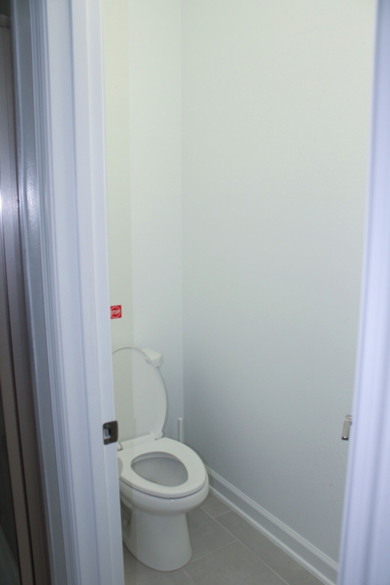 A small, white bathroom with a toilet, a white door, and a white wall.