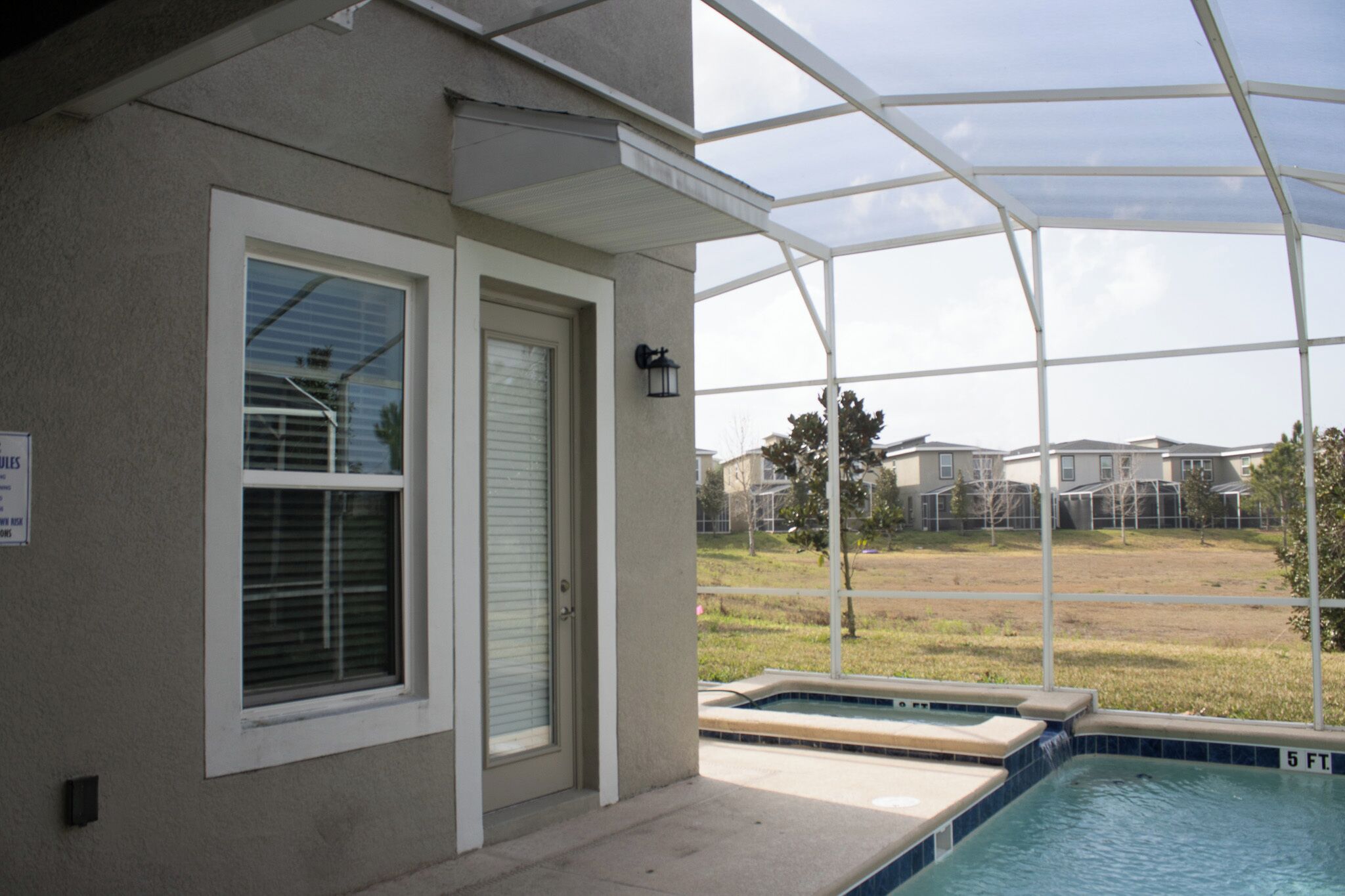 Zona de piscina exterior cubierta con vistas a un barrio residencial.
