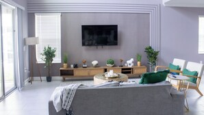 A modern living room with a flat-screen TV, a sofa, a coffee table, and a TV stand with decorative items.
