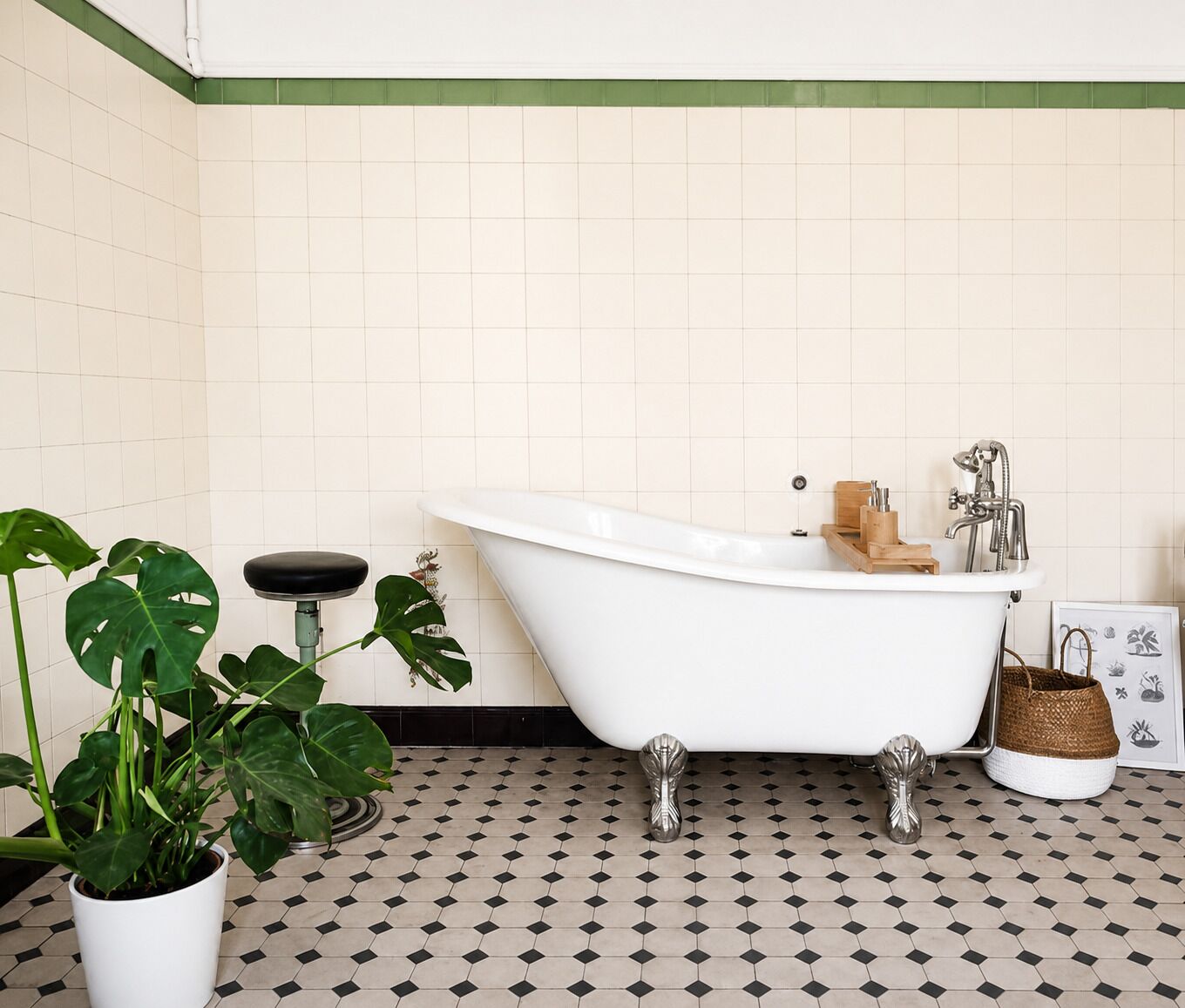 Une salle de bain avec une baignoire sur pieds, une plante en pot, un plateau en bois et une estampe botanique encadrée au mur.