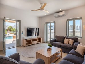 Ein modernes Wohnzimmer mit Flachbildfernseher, Deckenventilator, Sofa und Couchtisch.