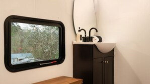 A bathroom with a window, a sink, and a wooden bench.