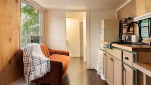 A compact kitchen with wooden cabinets, a countertop, and a window.