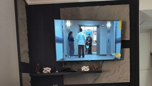 En platt-TV som är monterad på en vägg, med en soffa framför.