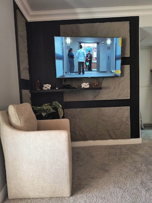 A flat-screen TV mounted on a wall with a sofa in front. - 1-bedroom condo in delightful, Arcadia area, Phoenix, AZ w/AC (Phoenix)