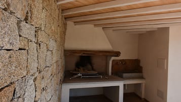 Una pared de piedra, techo de madera y un banco con chimenea.