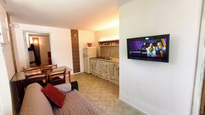 A living room with a TV, a dining area, and a kitchen. - Villa Teria, exclusive property! (Santa Maria Navarrese)