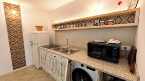 A compact kitchen with a washing machine, a microwave, a sink, and a refrigerator.