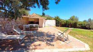 An outdoor patio with a stone wall, a grill, and seating. - Villa Teria, exclusive property! (Santa Maria Navarrese)