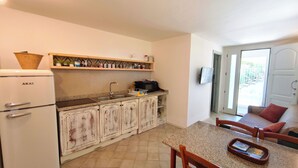 A compact kitchen with a refrigerator, microwave, and sink. There is a dining area with a table and chairs. - Villa Teria, exclusive property! (Santa Maria Navarrese)
