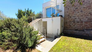 A modern building with a stone wall, a white exterior, and a blue door. - Villa Teria, exclusive property! (Santa Maria Navarrese)