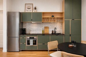 Eine moderne Küche mit Edelstahlkühlschrank, eingebautem Backofen und einem Essbereich mit rundem Tisch und Stühlen.