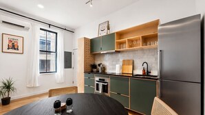 Et moderne køkken med spisebord, køleskab og et vindue med gardiner.