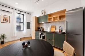 Een moderne keuken met een eettafel, een koelkast en een raam met gordijnen.
