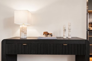 A dark wooden console table with a marble lamp, a small toy car, and two white candle holders. - Washington Park 2BR w Parking - Walk to All (Cincinnati)