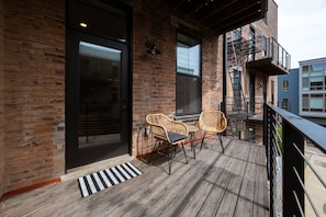 A wooden deck with two wicker chairs and a black metal railing. - Washington Park 2BR w Parking - Walk to All (Cincinnati)