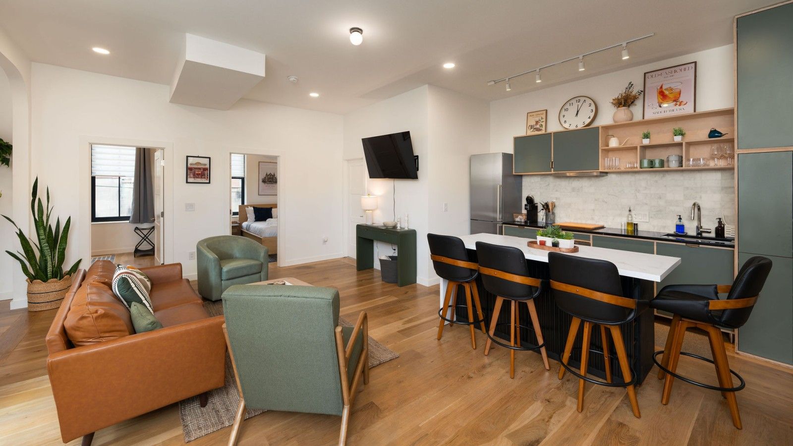 A modern living room with a sofa, chairs, and a dining area with bar stools.