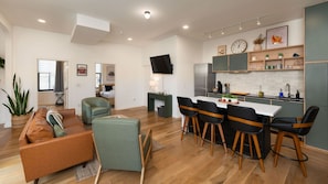 A modern living room with a sofa, chairs, and a dining area with bar stools. - Washington Park 2BR w Parking - Walk to All (Cincinnati)
