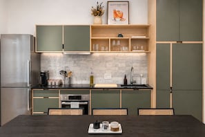 A modern kitchen with a built-in oven, a coffee maker, and a dining area with a table and chairs. - Washington Park 2BR w Parking - Walk to All (Cincinnati)