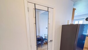 Une pièce avec une porte blanche, un panier à linge de couleur beige et un réfrigérateur de couleur foncée.