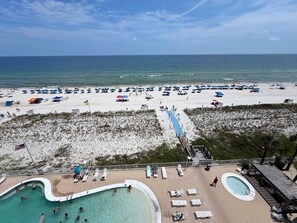 A beach with a swimming pool, lounge chairs, and umbrellas. - New Listing - Fresh Calendar | Beachfront Condo | Private Balcony | Pool (Gulf Shores)