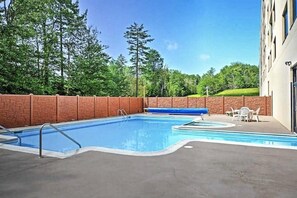 A rectangular swimming pool with a brick wall and a blue water slide. - SC 2309: Stylish Summer Retreat with Pool Access & Mountain Charm (Snowshoe)