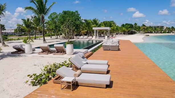 Ein Resort mit Holzterrasse, Liegestühlen, Pool und Strand.