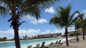 Ein Strand mit Liegestühlen, Palmen und einem Pool.