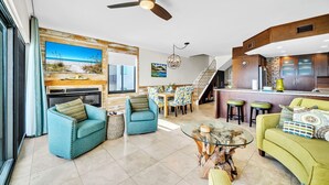 A modern living room with a ceiling fan, a dining area, and a kitchen with a bar. - The Coastal View Gulf Front Condo in Seagrove Beach Sleeps 7 with a Pool (Santa Rosa Beach)