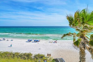 Ein Strand mit klarem türkisblauem Wasser, weißem Sand und Palmen.