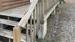Une cabane en bois avec une véranda, une porte et une fenêtre.