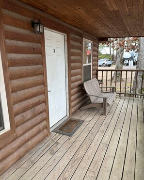 A log cabin with a porch, a white door marked with the number 3, and a bench. - Cozy Cabin #3 Near Lake Merrisach in Tichnor AR (Tichnor)