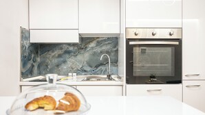 A modern kitchen with a marble backsplash, stainless steel appliances, and a glass display case with pastries. - Apartment near the center and the sea, cozy for families and copies (San Benedetto del Tronto)