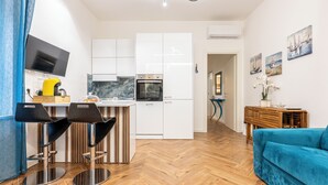 A modern kitchen with white cabinets, a built-in oven, and a bar area with two stools. - Apartment near the center and the sea, cozy for families and copies (San Benedetto del Tronto)