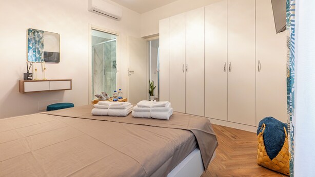 A modern hotel room with a large bed, a bedside table with toiletries, a wardrobe, and a television. - Apartment near the center and the sea, cozy for families and copies (San Benedetto del Tronto)