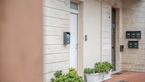 A building with a white wooden exterior, a door, and two potted plants on the ground. - Apartment near the center and the sea, cozy for families and copies (San Benedetto del Tronto)