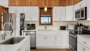 A modern kitchen with white cabinets, stainless steel appliances, and a wooden ceiling. - South Nags Head 4-Bedroom House Ocean & Sound Views  Hot Tub and Community Pool (Nags Head)