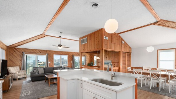 A modern loft-style living space with a large kitchen island, wooden accents, and a dining area. - South Nags Head 4-Bedroom House Ocean & Sound Views  Hot Tub and Community Pool (Nags Head)