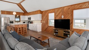 A modern kitchen with white cabinets, a central island, and a large TV. - South Nags Head 4-Bedroom House Ocean & Sound Views  Hot Tub and Community Pool (Nags Head)