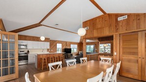 A spacious kitchen with wooden cabinets, a central island, and a dining area with a large table and chairs. - South Nags Head 4-Bedroom House Ocean & Sound Views  Hot Tub and Community Pool (Nags Head)